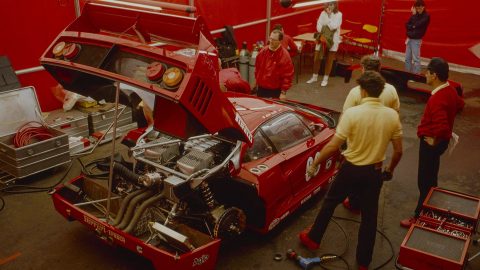 Meccanici in tuta rossa al lavoro sulla Ferrari F40 con cofano aperto nel box