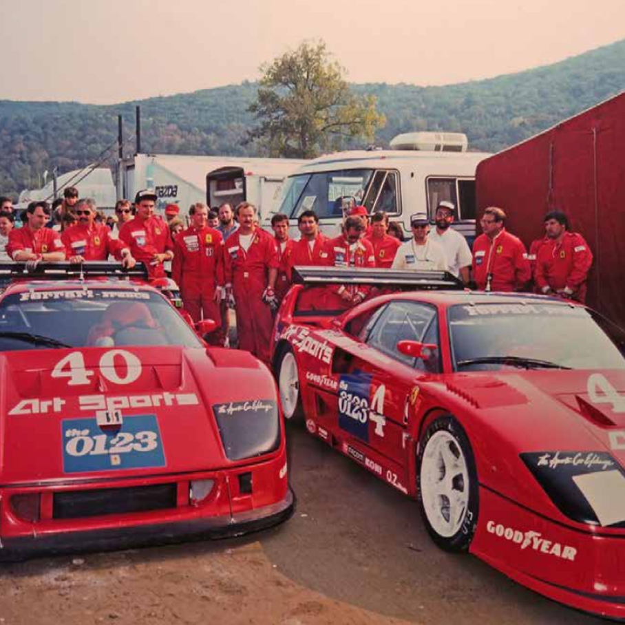 Full team lined up behind the two Ferrari F40 Competizione numbers 40 and 4 in the paddock