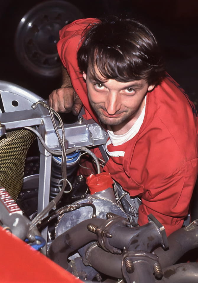 Portrait of Francesco Calzavara in red overalls working in the Ferrari F40 engine bay