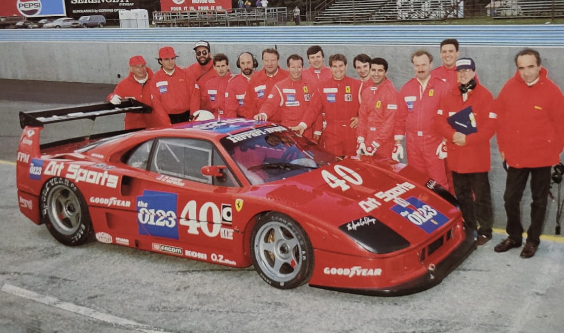 AC Motorsport team lined up behind the Ferrari F40 number 40 Art Sports in the circuit pit lane