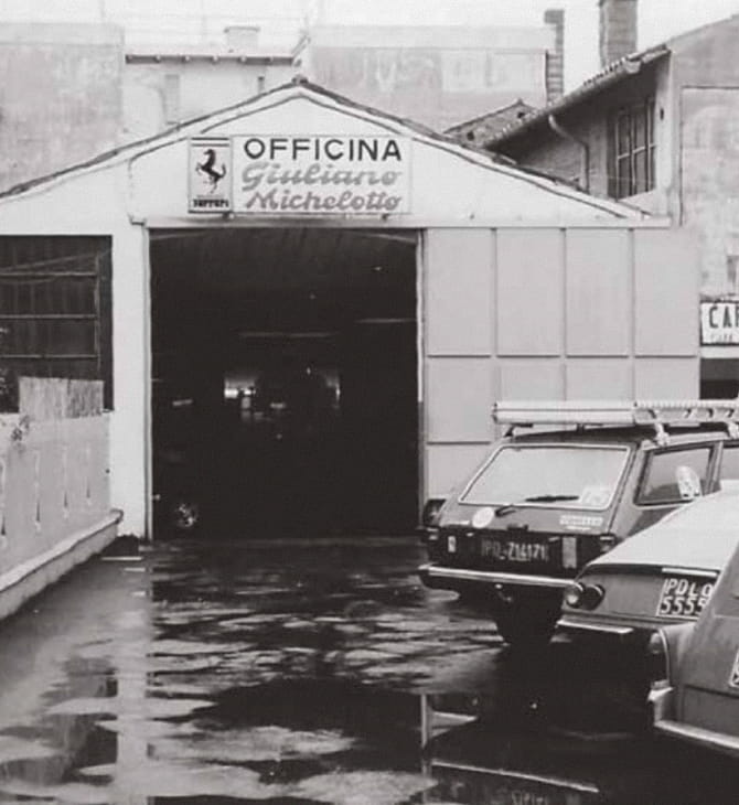 Exterior of Officina Giuliano Michelotto in Padua with sign and Ferrari logo, black and white photo