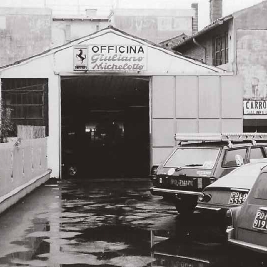 Exterior of Officina Giuliano Michelotto in Padua with sign and Ferrari logo, black and white photo
